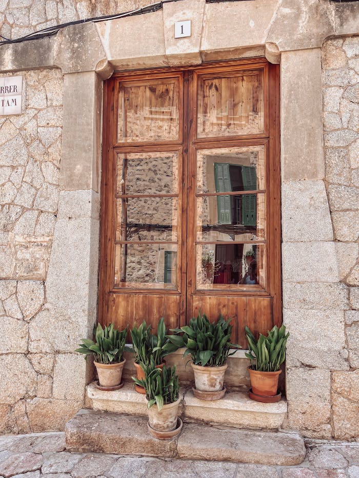 services-01 Rustic wooden door with potted plants in historic Valldemossa, Spain's charming architecture.